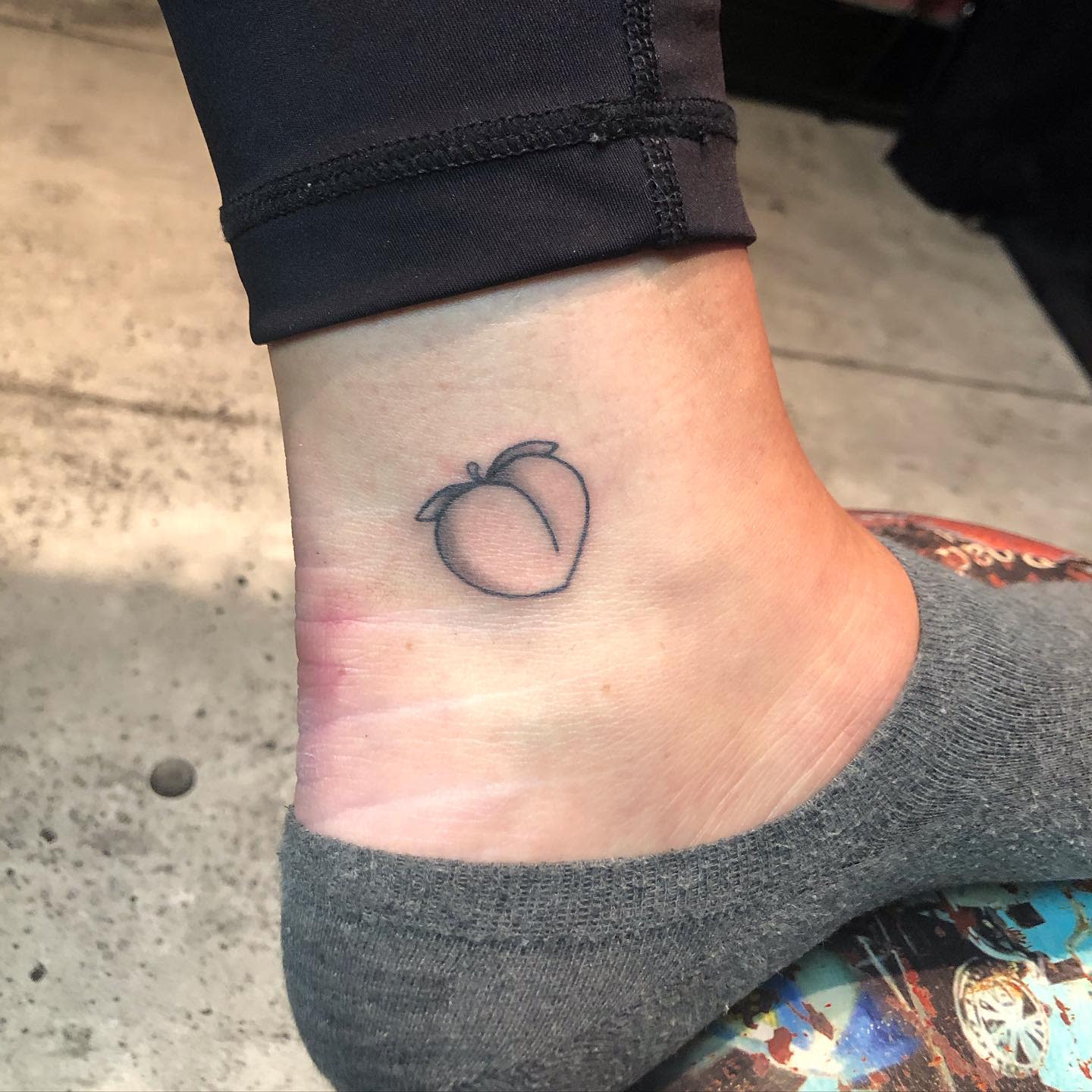 Simple outline of a peach tattoo on an ankle